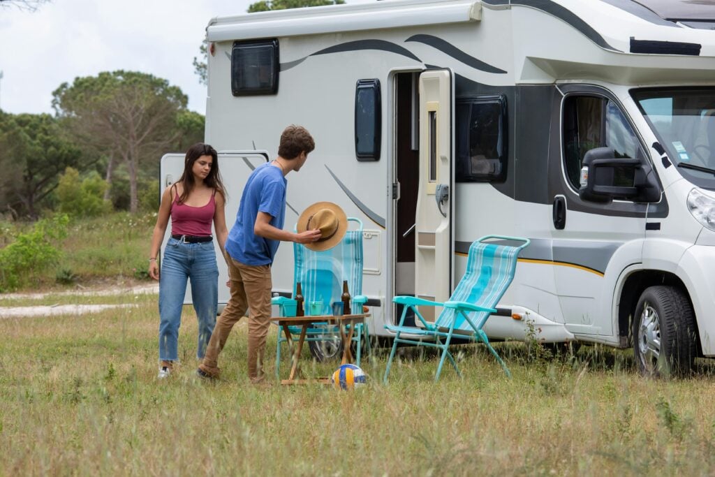 Outdoor scene of a young couple setting up camp next to their Recreational Vehicle